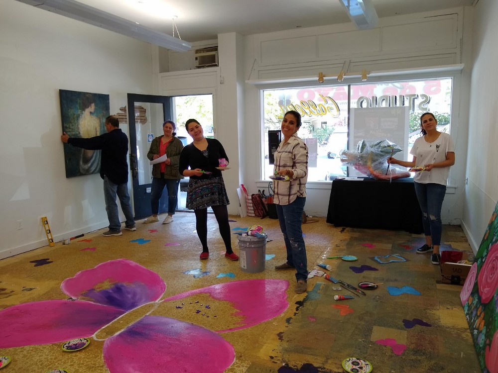 Las artistas preparándo la galería para la inauguración. Pintado del piso con emblema mariposa.